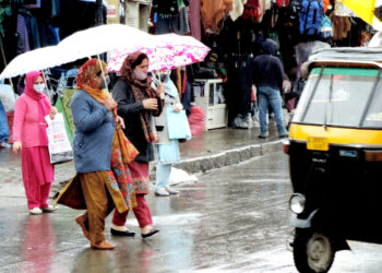 SRINAGAR, APR 15 (UNI) Women walking down the Lal Chowk in Srinagar amid rain fall on Thursday. UNI SRN PHOTO 1