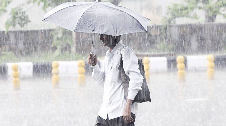 New Delhi: A man shields himself with an umbrella as heavy rains lash Delhi, on July 22, 2018. (Photo: IANS)